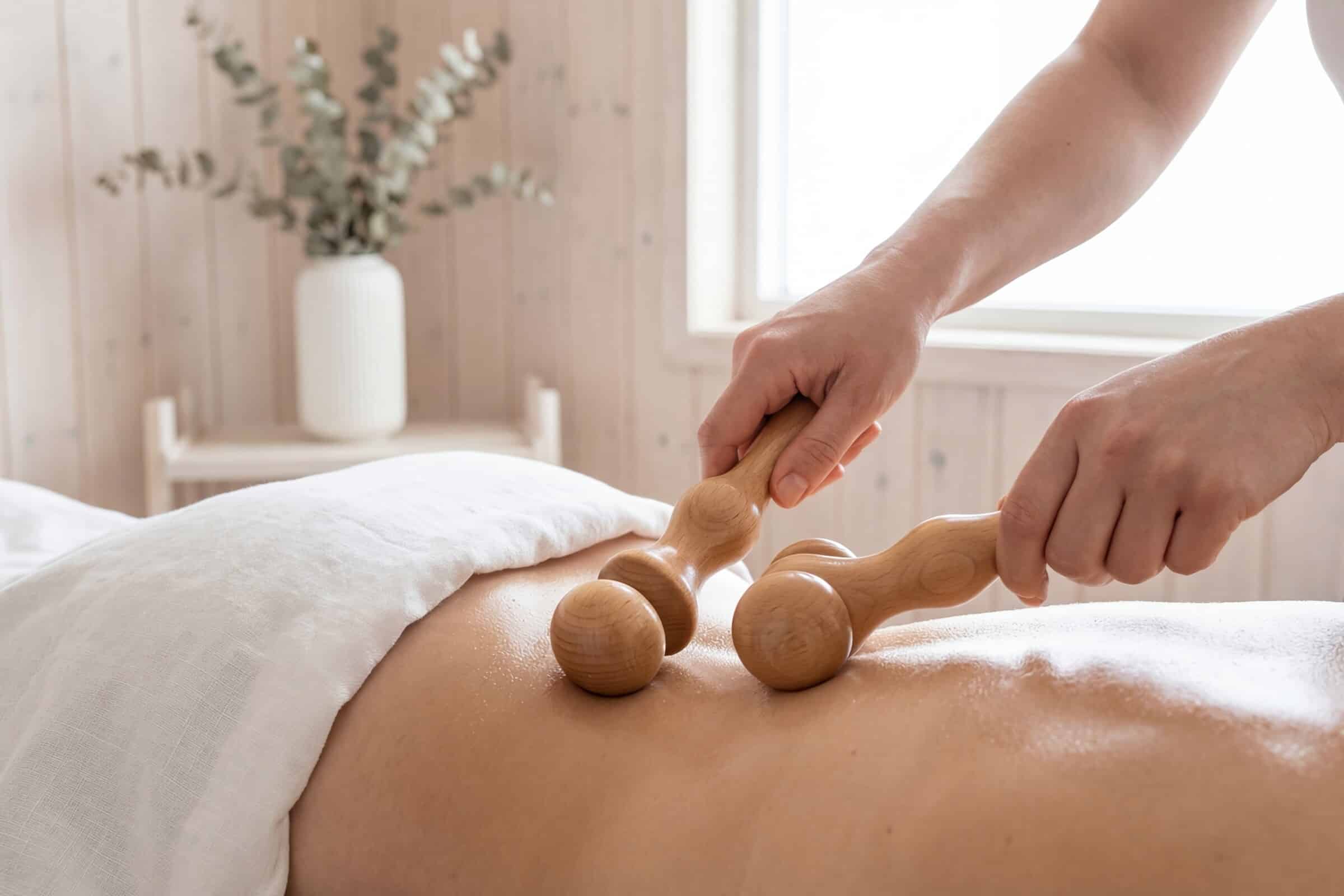 Holzrollen bearbeiten den Rücken während einer Maderotherapie-Sitzung