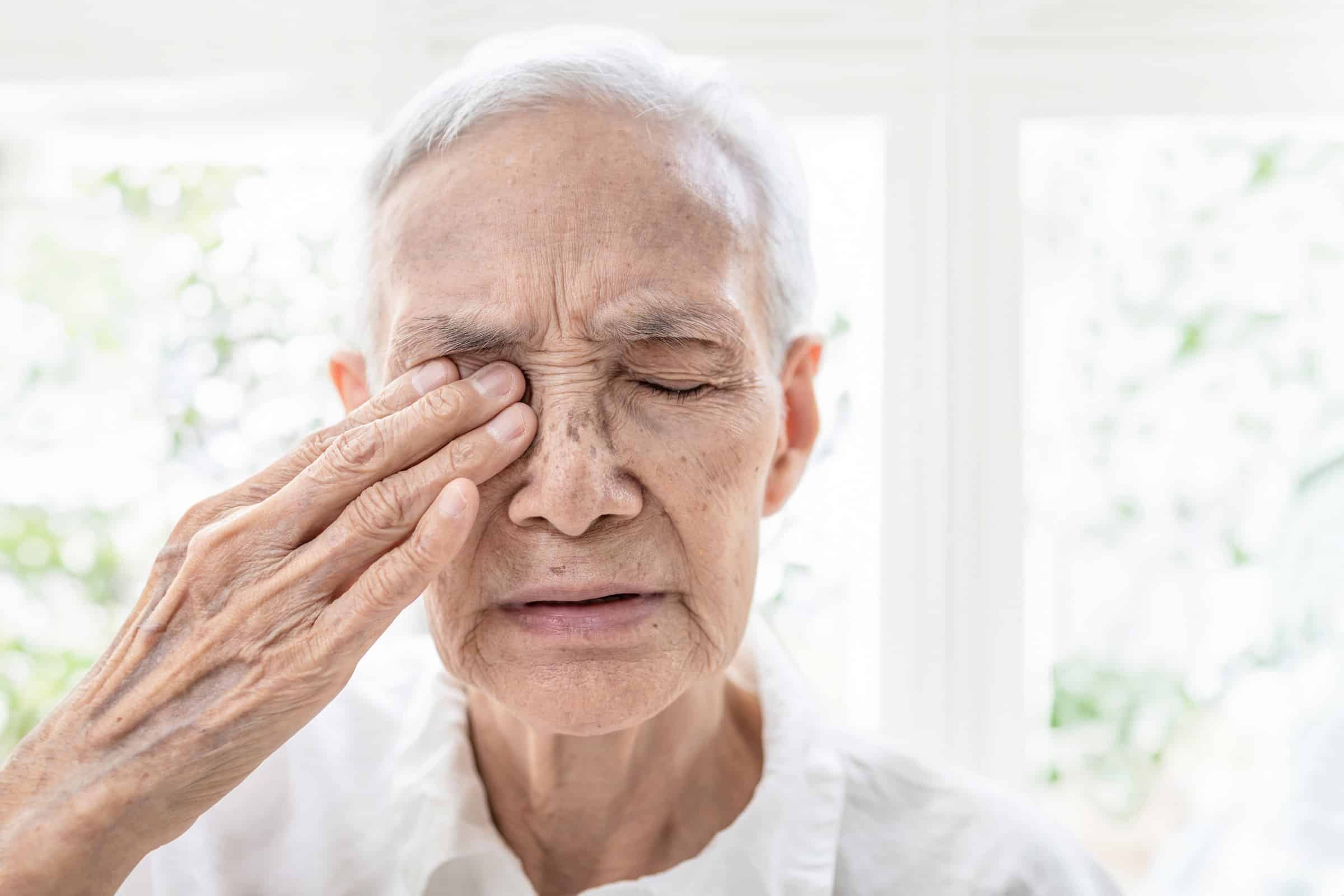 Älterer Mann reibt sich das Auge und hat Beschwerden beim Sehen