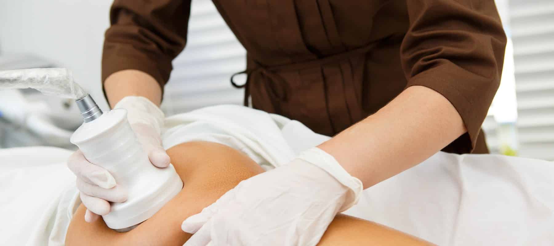 Kosmetikerin führt eine Vakuummassage am Bein einer Kundin durch