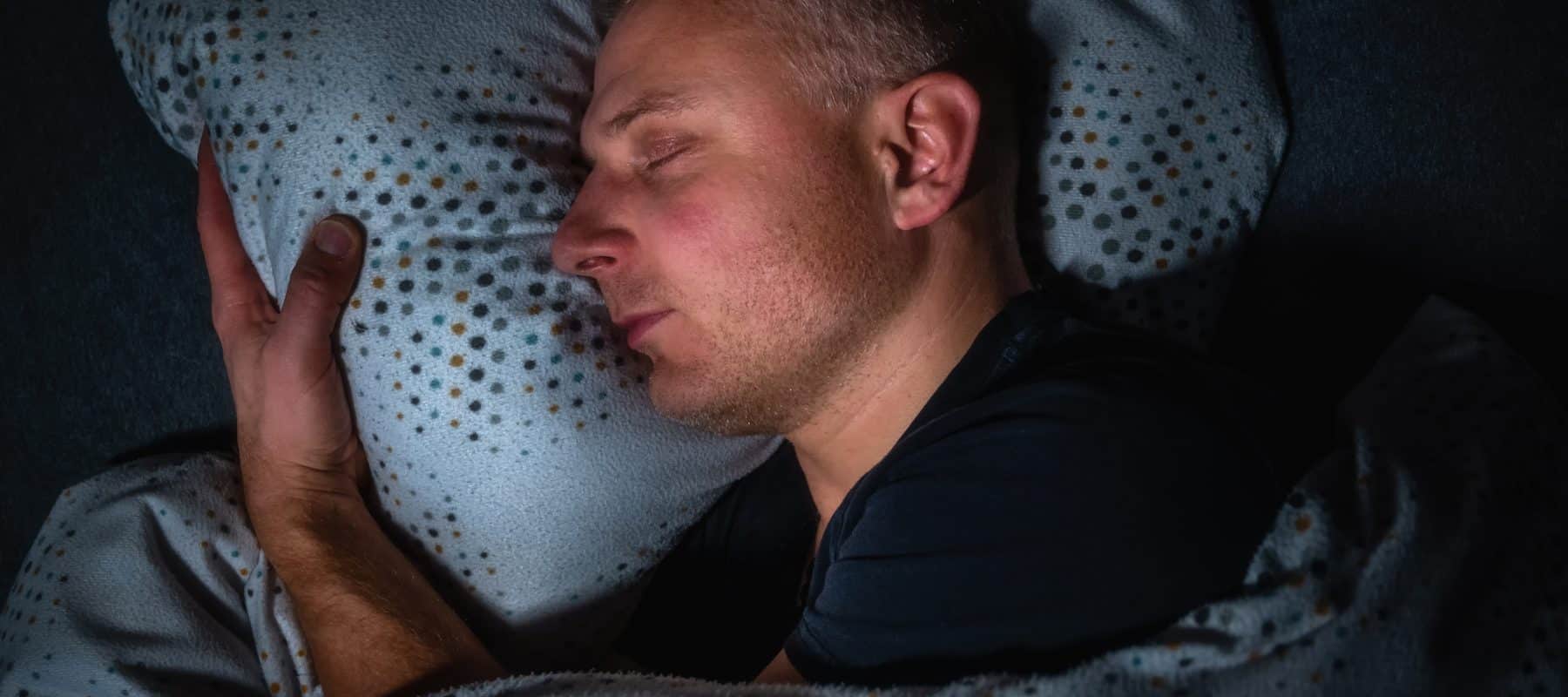 Frau schläft friedlich in einem dunklen Schlafzimmer