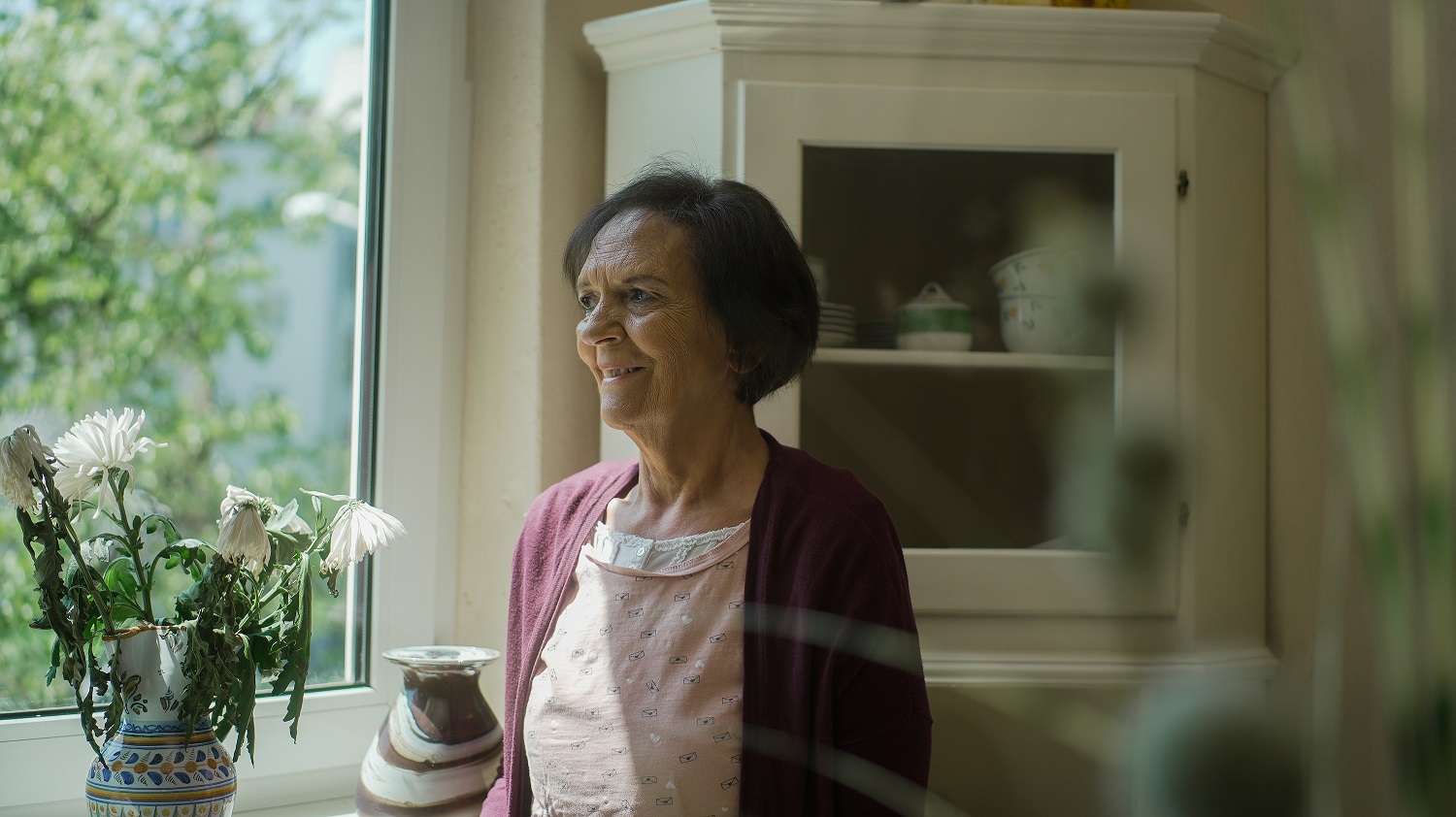 Ältere Frau als Patientin in dem DAKOS Pflegedienst schaut aus dem Fenster